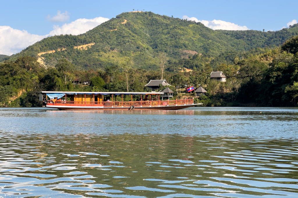 Ein grösseres Touristenboot kreuzt den Fluss