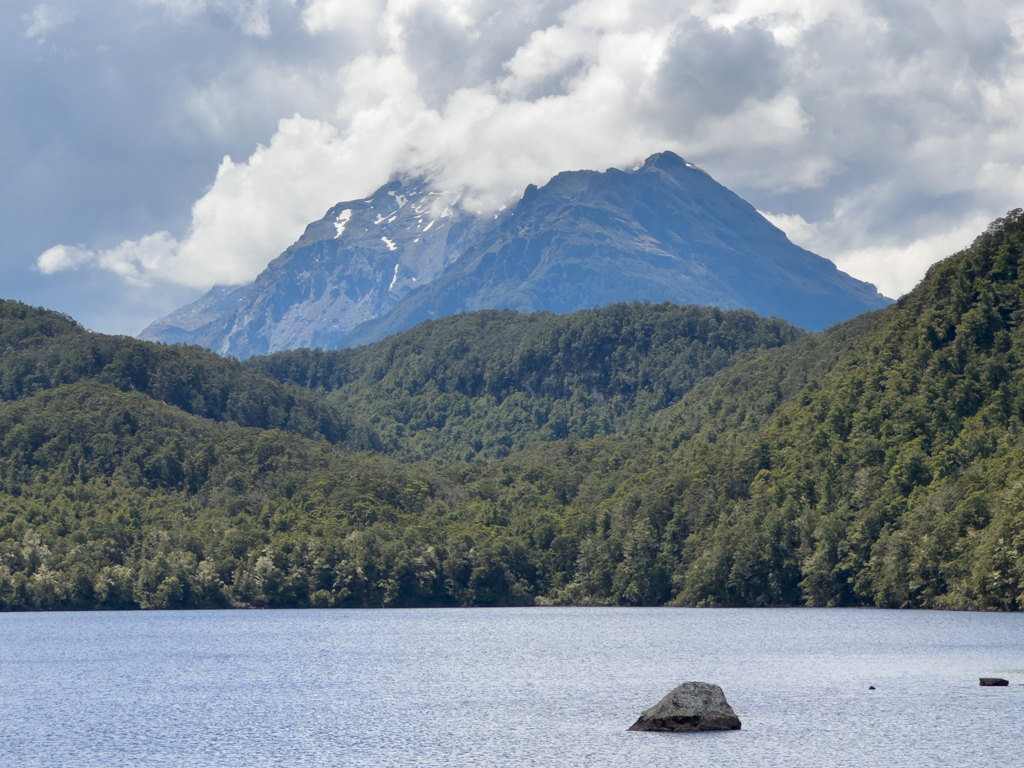 Weisse Wolken fangen sich an der Bergspitze