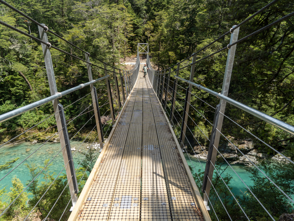 Jo posiert auf der Hängebrücke über den türkisfarbenen Routeburn River