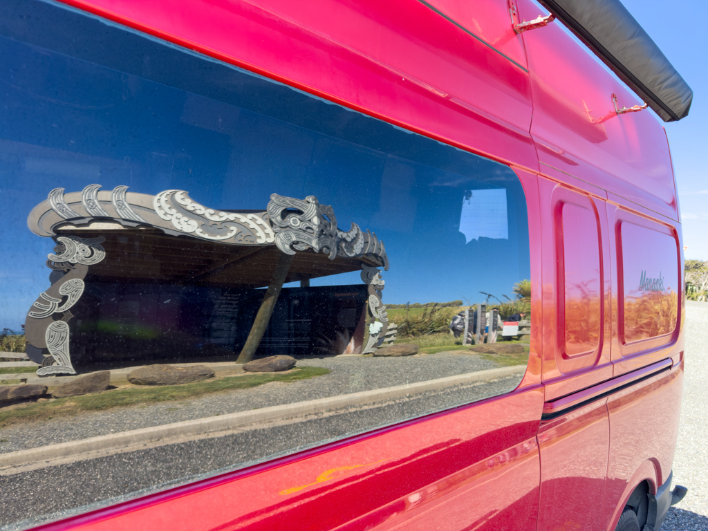 Der moderne, mit Maori Ornamenten verzierte Infostand am Slope Point spiegelt sich in Manaakis Seitenfenster