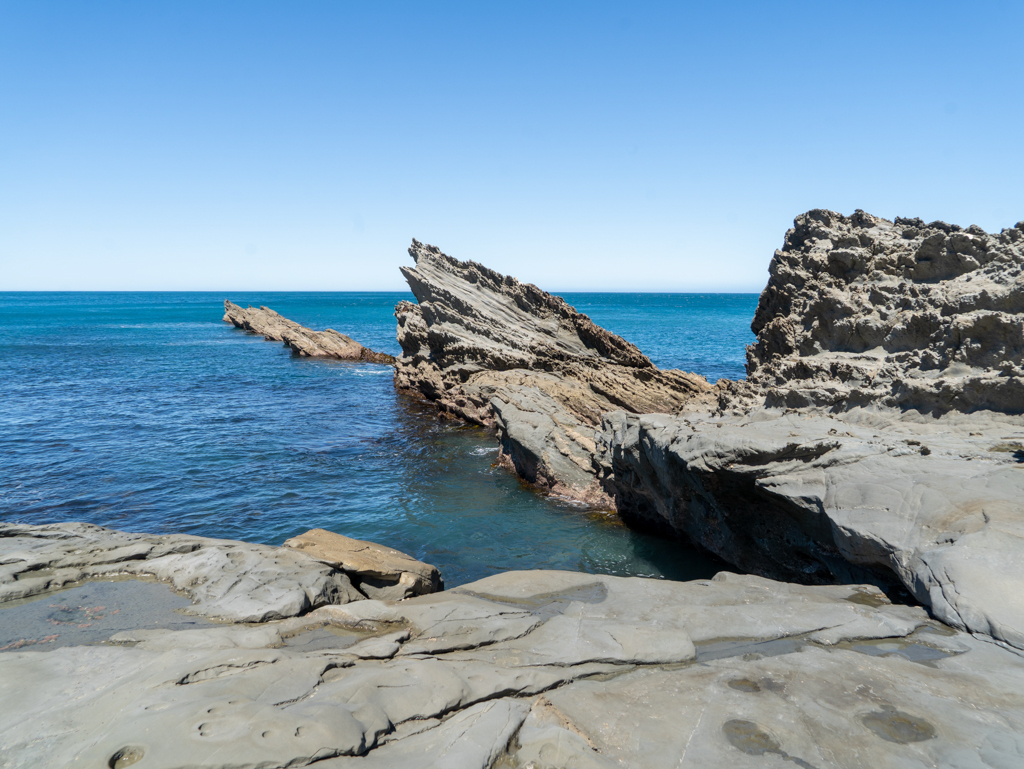 Schräge Felsen ragen aus dem Wasser in der Palliser Bay