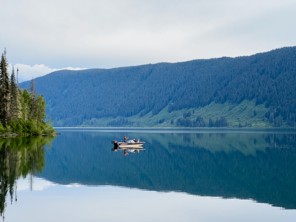 Ein Paar geht abends mit ihrem Motorbötchen fischen im ruhigen, spiegelnden Meziadin Lake