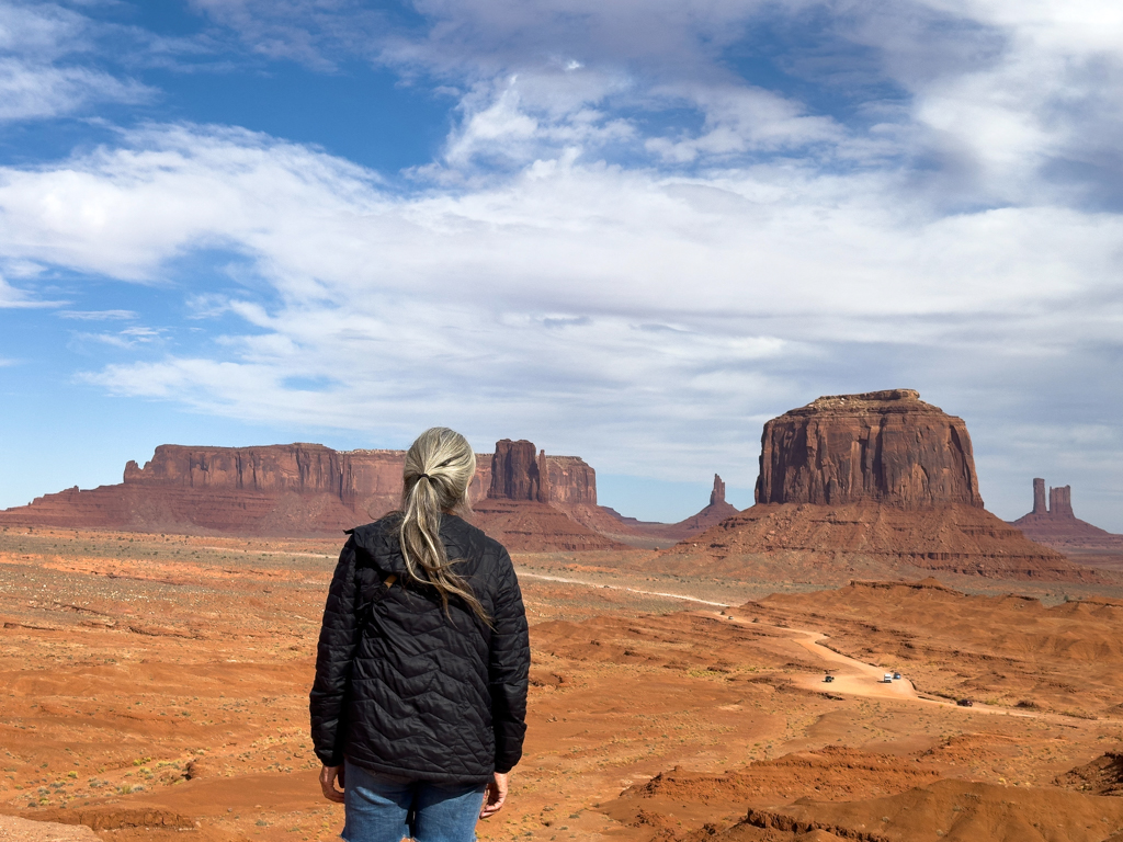 Im Hintergrund Sentinel Mesa. Ma posiert vor Merrick Butte links daneben East Mitten Butte während der Tour durch das Monument Valley