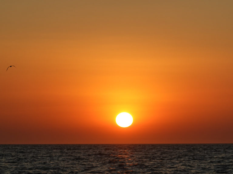 Kurz bevor die Sonne hinter dem Horizont verschwindet. Ein roter Himmel über dem Meer