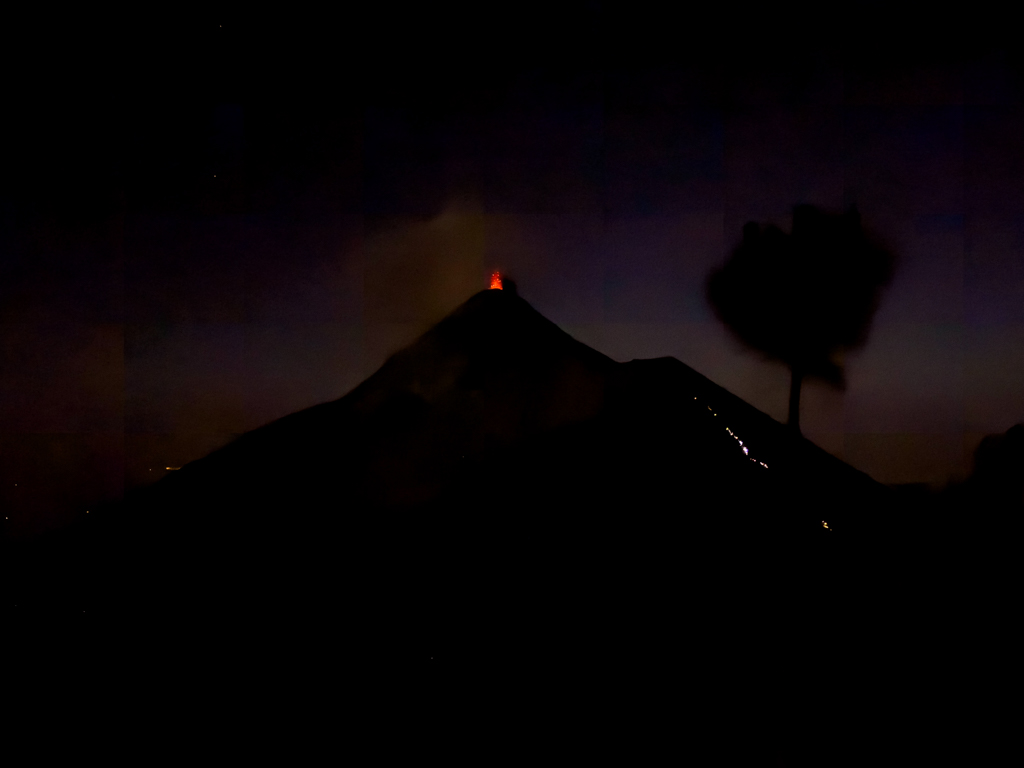 Fuego spuckt Feuer und Rauch in der Nacht. Rechts die Lichterschlange einer Gruppe die auf dem Retourweg sind