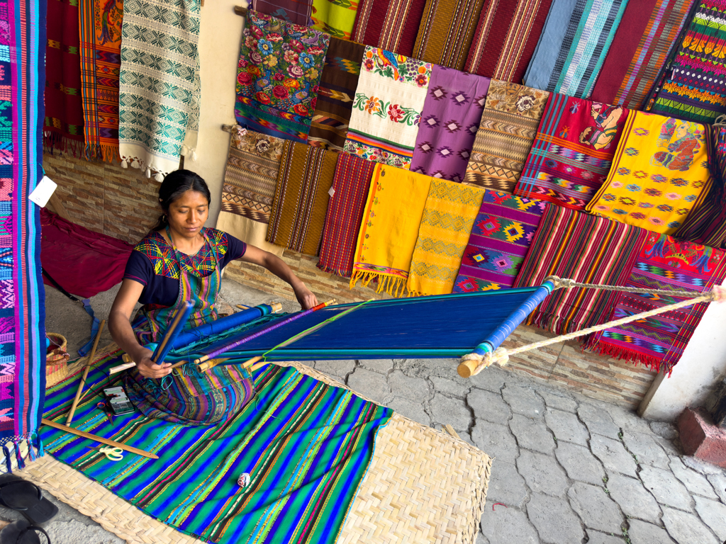 Eine Maya Frau webt auf einem traditionellen Webrahmen einen traditionellen Stoff