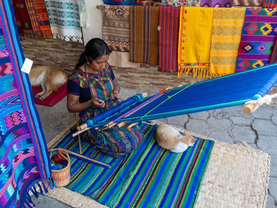 Eine Maya Frau webt auf einem traditionellen Webrahmen einen traditionellen Stoff