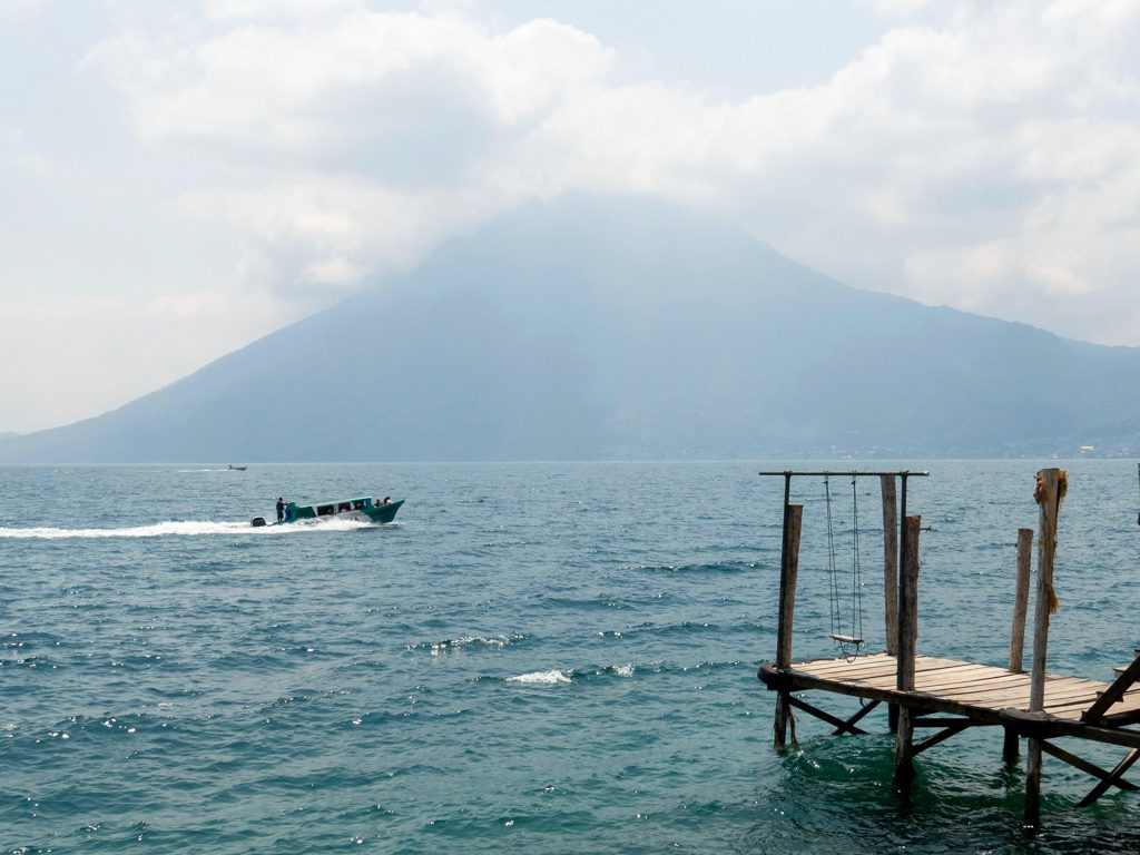 Nachbarbootssteg mit Schaukel hier am Lago Atitlán. Dahinter ein paar Boote die den See kreuzen