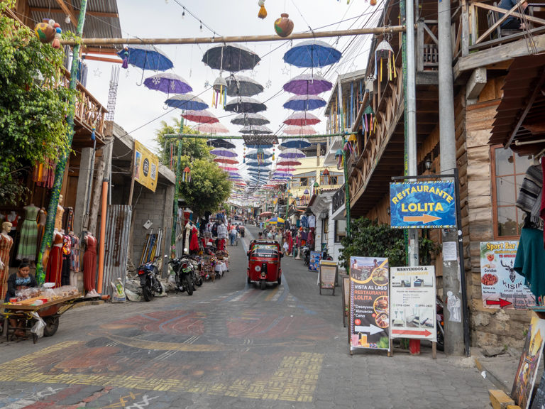 steile bunte Hauptstrasse in San Juan mit Regen/ Sonnenschirmen als Schattenspender