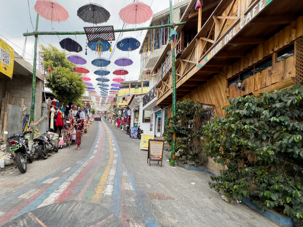 steile bunte Hauptstrasse in San Juan mit Regen/ Sonnenschirmen als Schattenspender
