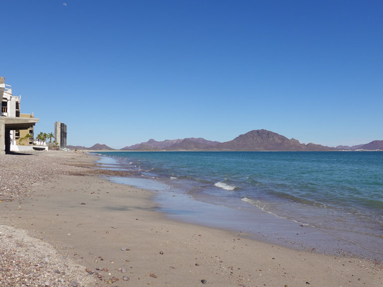 Strand von San Carlos mit riesigem Hotel-Wolkenkratzer im Rohbau