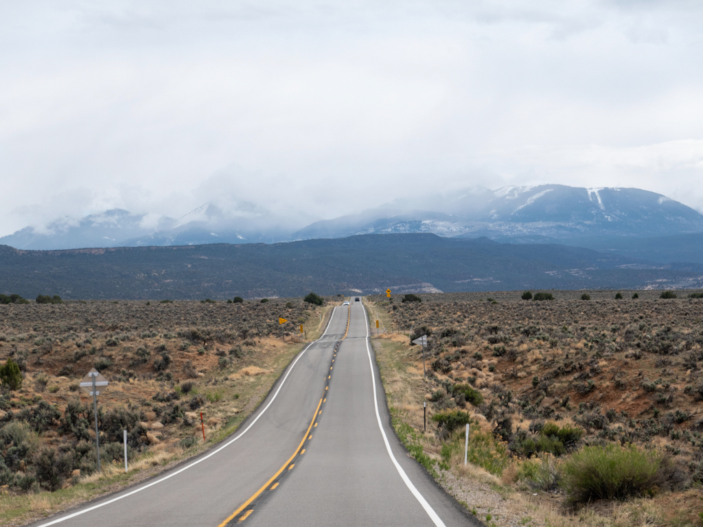 Strasse zum Needles District im Canyonlands Nationalpark - im Hintergrund die schneebedeckten Berge