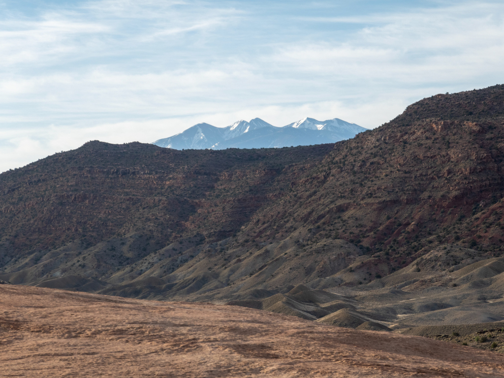 Gigantische Felswände, Erosionen und Ebenen im Arches NP. Dahinter hohe weisse Bergspitzen
