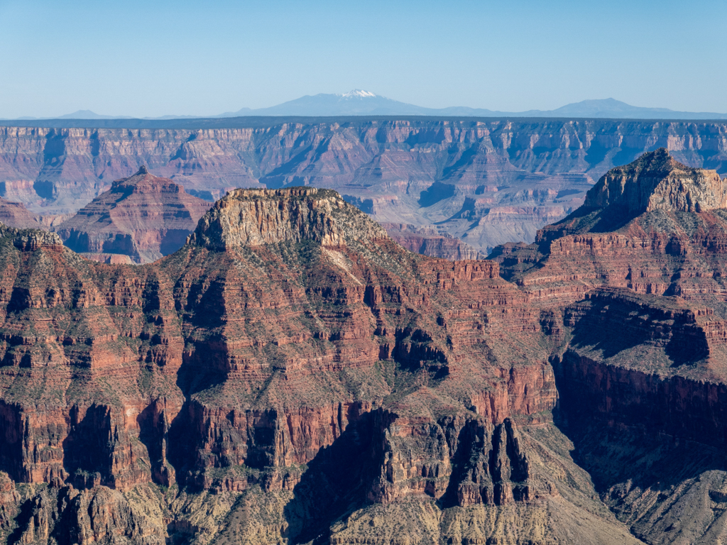 Blick vom North Rim in den gewaltigen Grand Canyon. Dahinter ein paar Schneeberge...