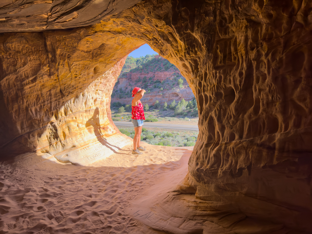 Ma am Ausgang einer der Sand Caves bei Kanab, auf einer Felswand hoch über dem Tal