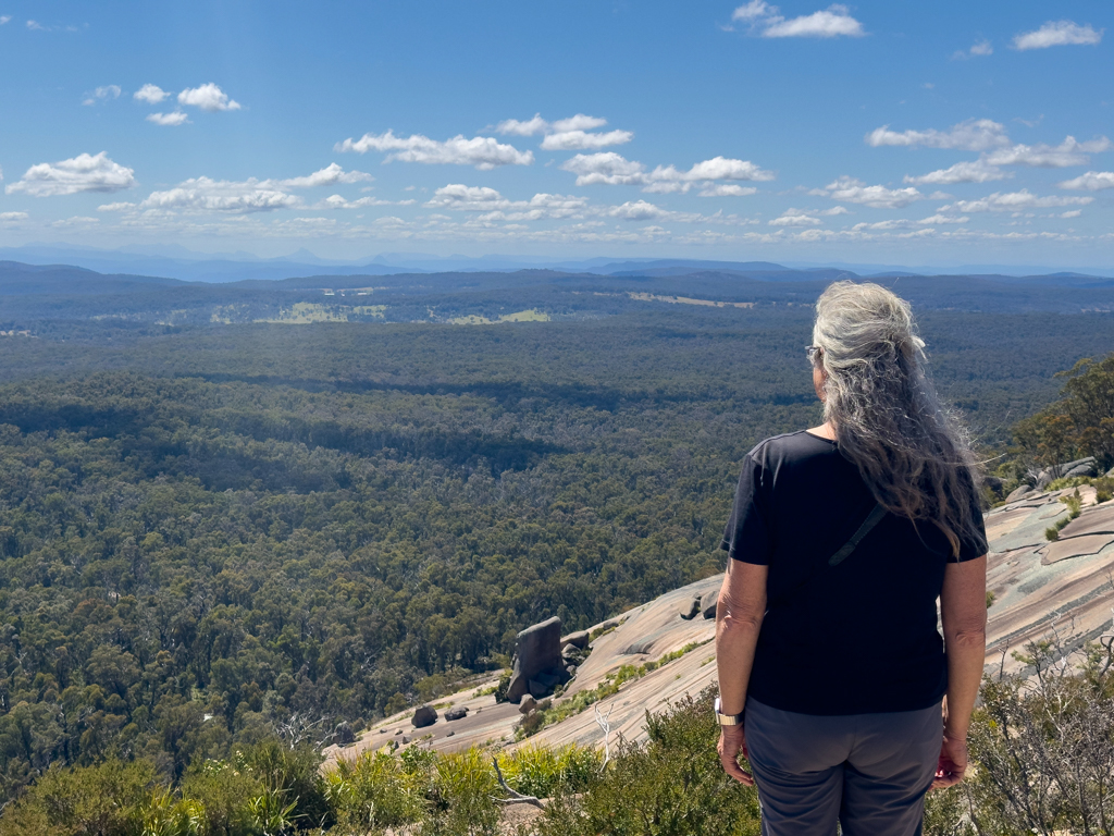 Ma schaut von der Kuppe des Bald Rocks auf das grüne, flache westliche Queensland