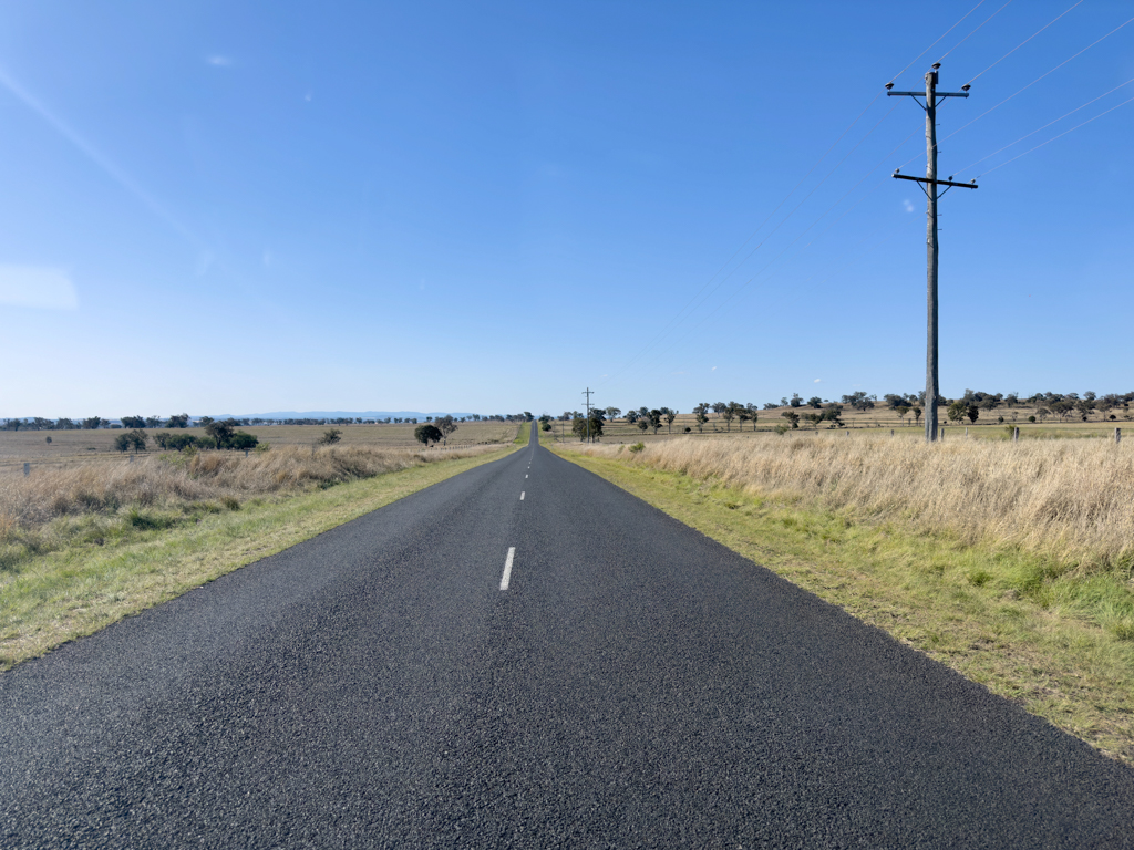 Eine einsame Strasse zwischen den weiten Feldern in Queensland