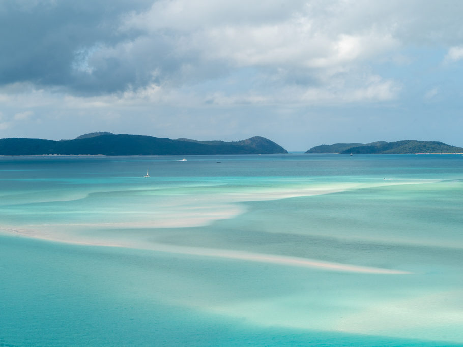 Alles Ton in Ton: Türkis farbenes Wasser, die Inseln schimmern bläulich vor einem blauem Himmel über Withunday Islands