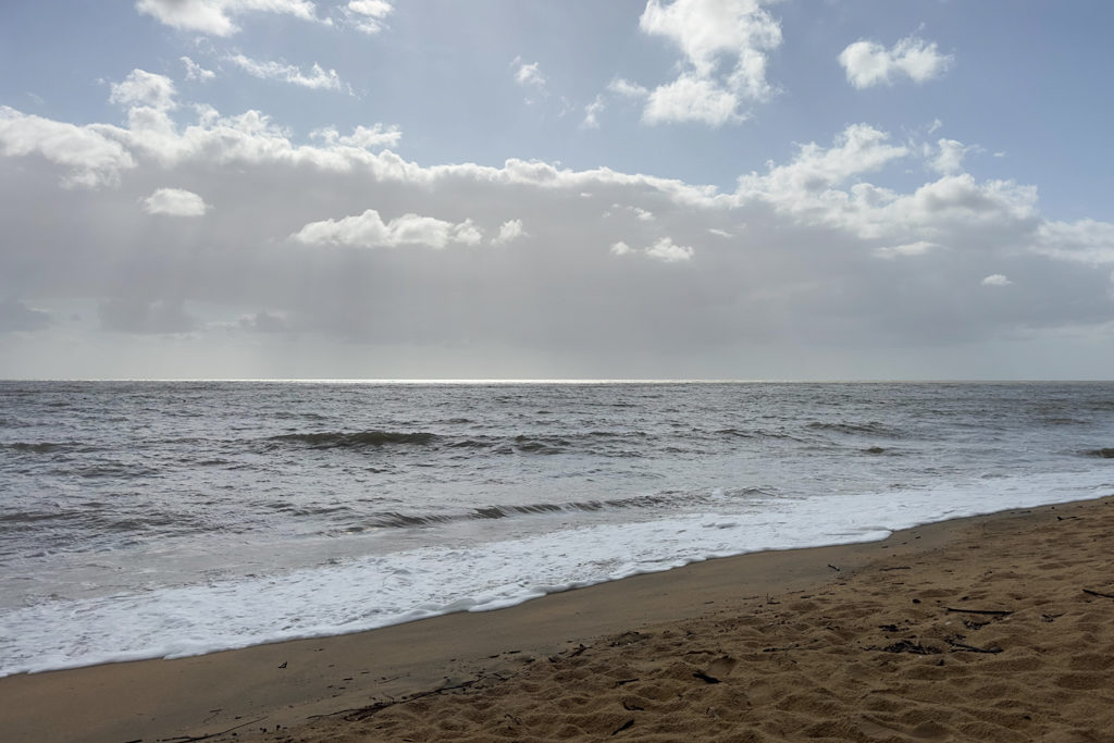 Die Sonne sticht durch die Wolkendecke und lasst die See am Horizont silbrig glitzern