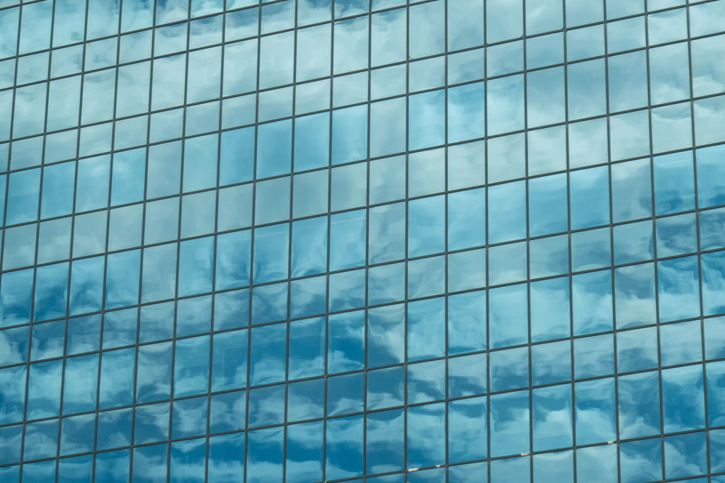 Der blaue Himmel spiegelt sich in der Glasfassade eines Hochhauses am Hafen von Sydney