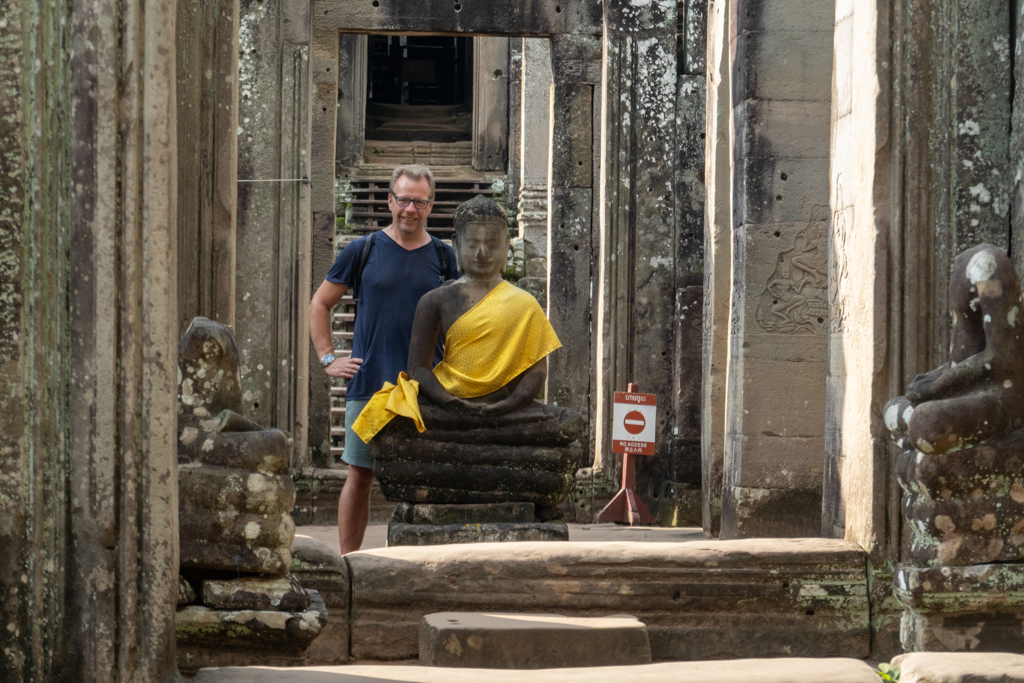 Jo in einem Kreuzgang hinter einem kleinen geschmückten Buddha