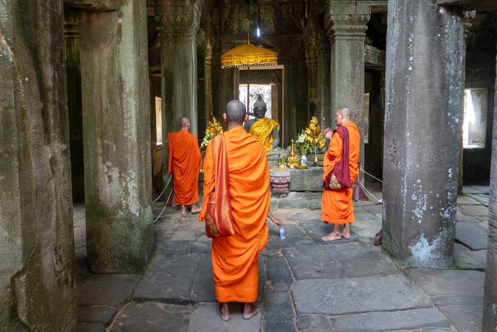 barfuss gehende Mönche beten zu dem geschmückten Buddha