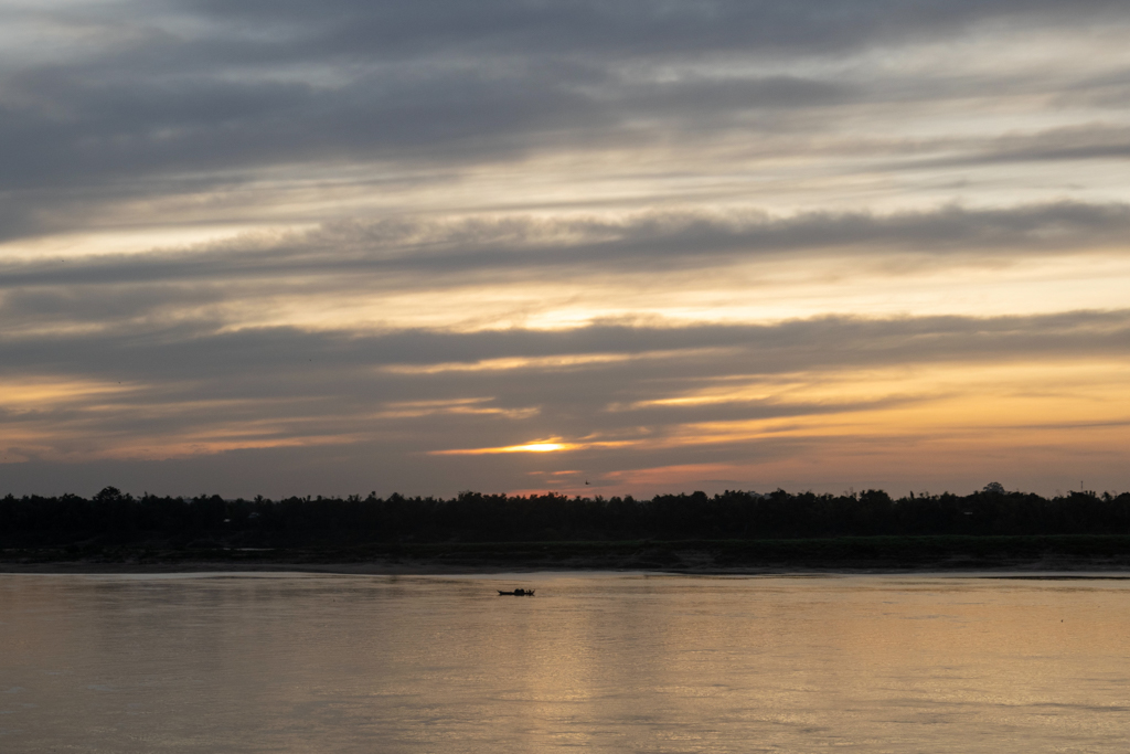 Der Mekong. Die Sonne verbirgt sich zum Sonnenuntergang hinter milchigen Wolken.