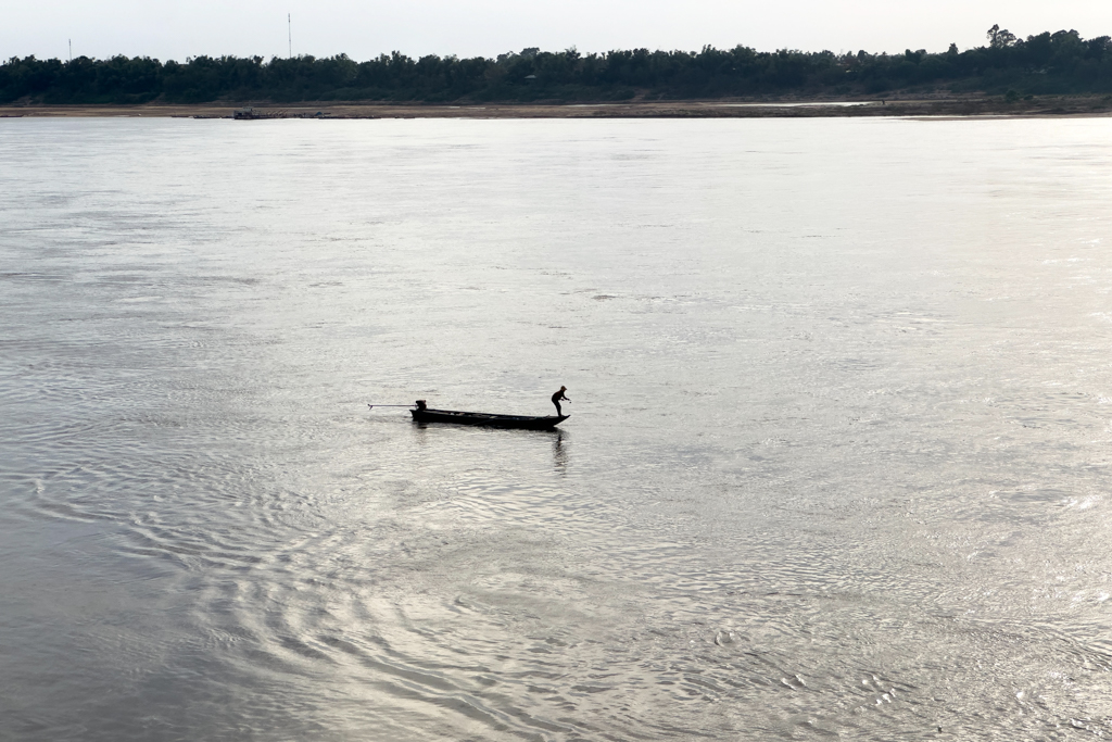 Ein kleines Fischerboot bei Kratie auf dem Mekong. Der Fischer holt sein Netz ein