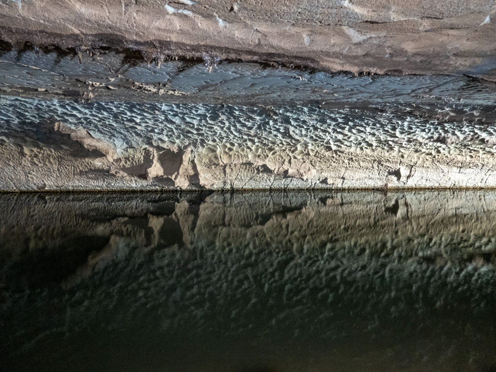 im Licht der Scheinwerfer spiegelt sich die Wasseroberfläche an den Wänden der Dragon Cave wieder