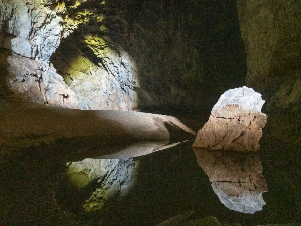 Tageslicht dringt bis hierhin in die Höhle ein. Ein Fels spiegelt sich im Wasser