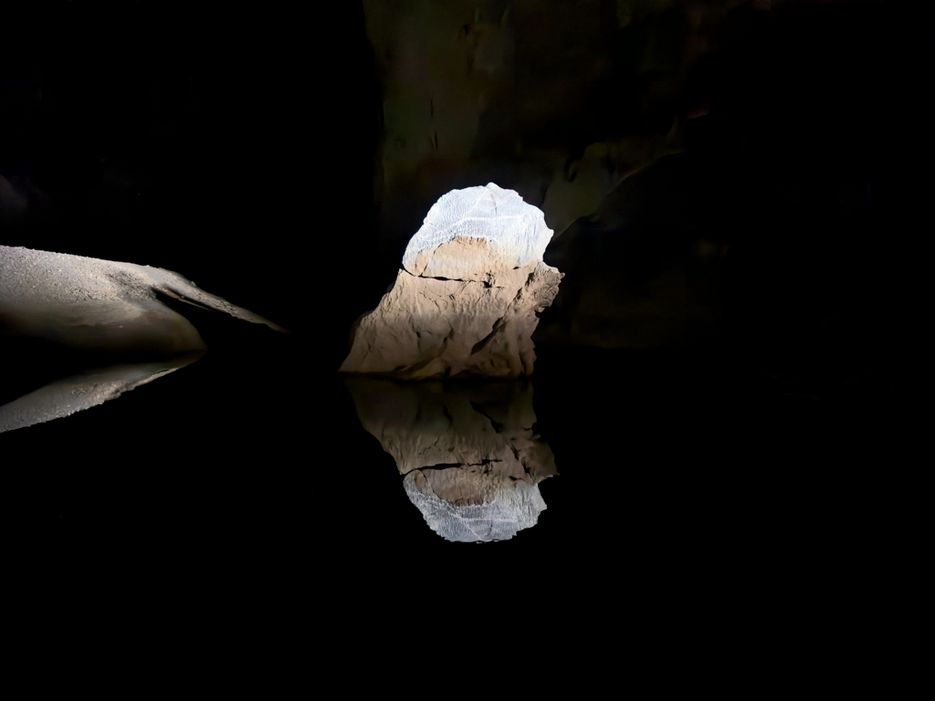 Ein Fels spiegelt sich im Wasser im einfallenden Tageslicht