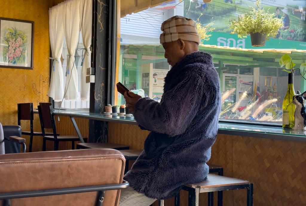 Trotz Sonnenschein. Ein Thai im langen Faserpelz mit typischer Mütze