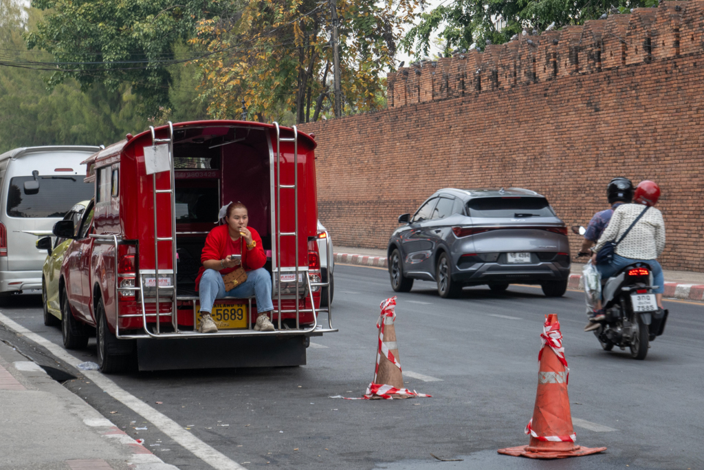 Essend, mit einem Telefon in der Hand wartet dieses Taxifahrerin auf Passagiere