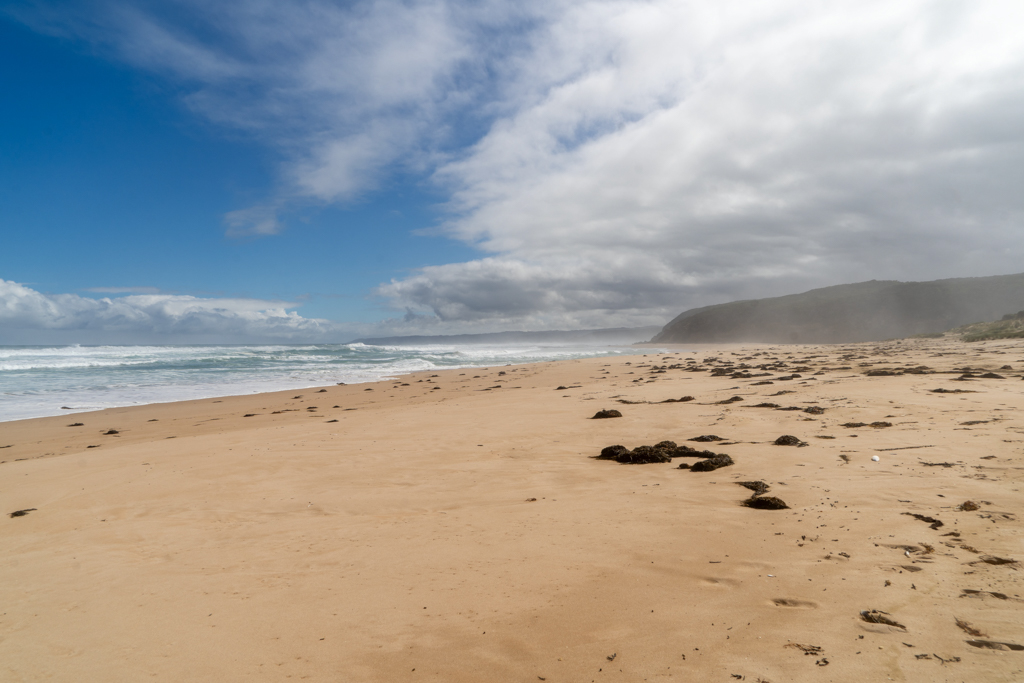Auch an diesem Strand treibt der Wind Sand und Gischt vor sich her...
