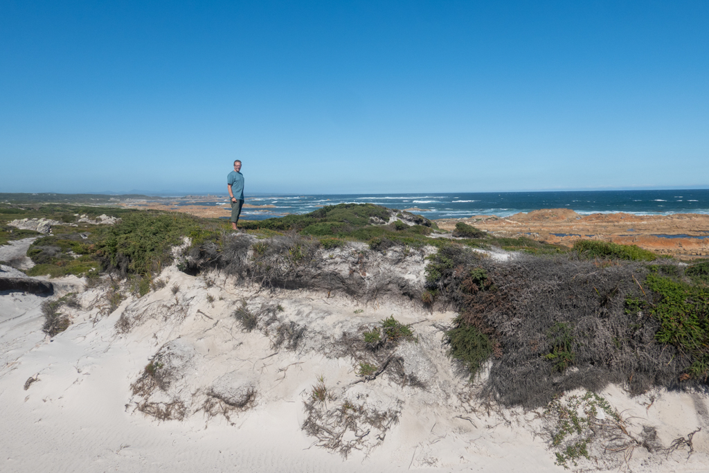 Jo posiert am Bluff Hill Point, dahinter die felsige Küste bei Ebbe