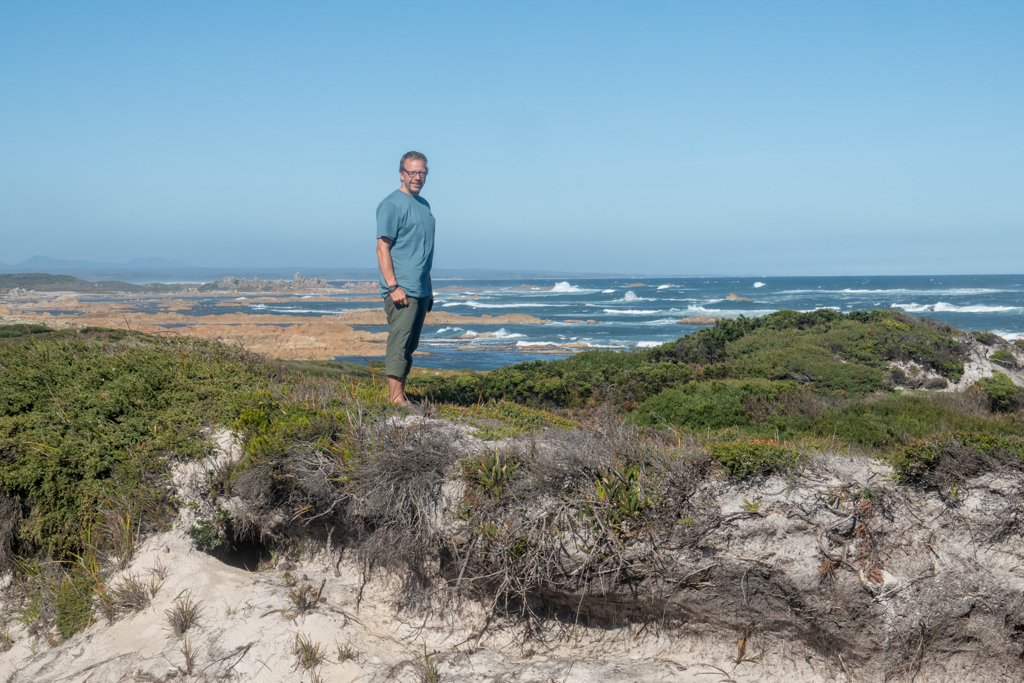 Jo posiert am Bluff Hill Point, dahinter die felsige Küste bei Ebbe