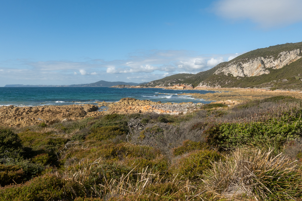 Blick auf die rötlichen Felsen der Bucht bei der South Cave im Rocky Cave N.P.
