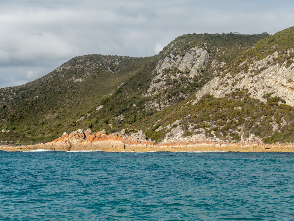 Blick auf die rötlichen Felsen der Bucht bei der South Cave im Rocky Cave N.P.
