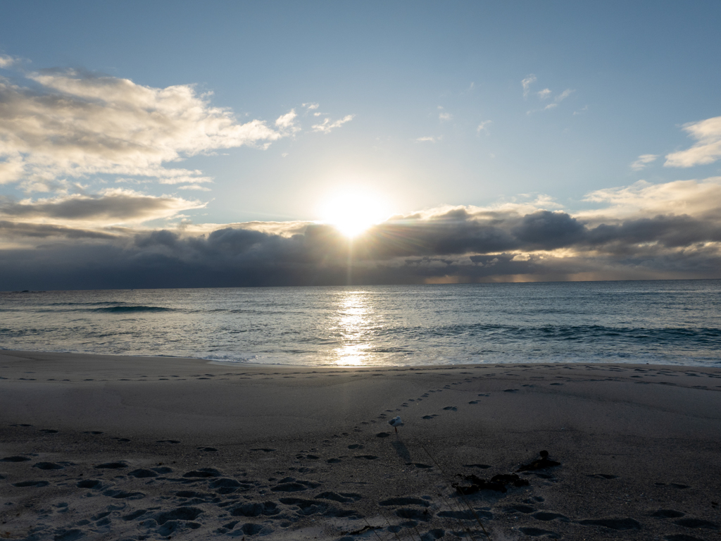 Die Morgensonne kommt über dem Wolkenband am Horizont hervor