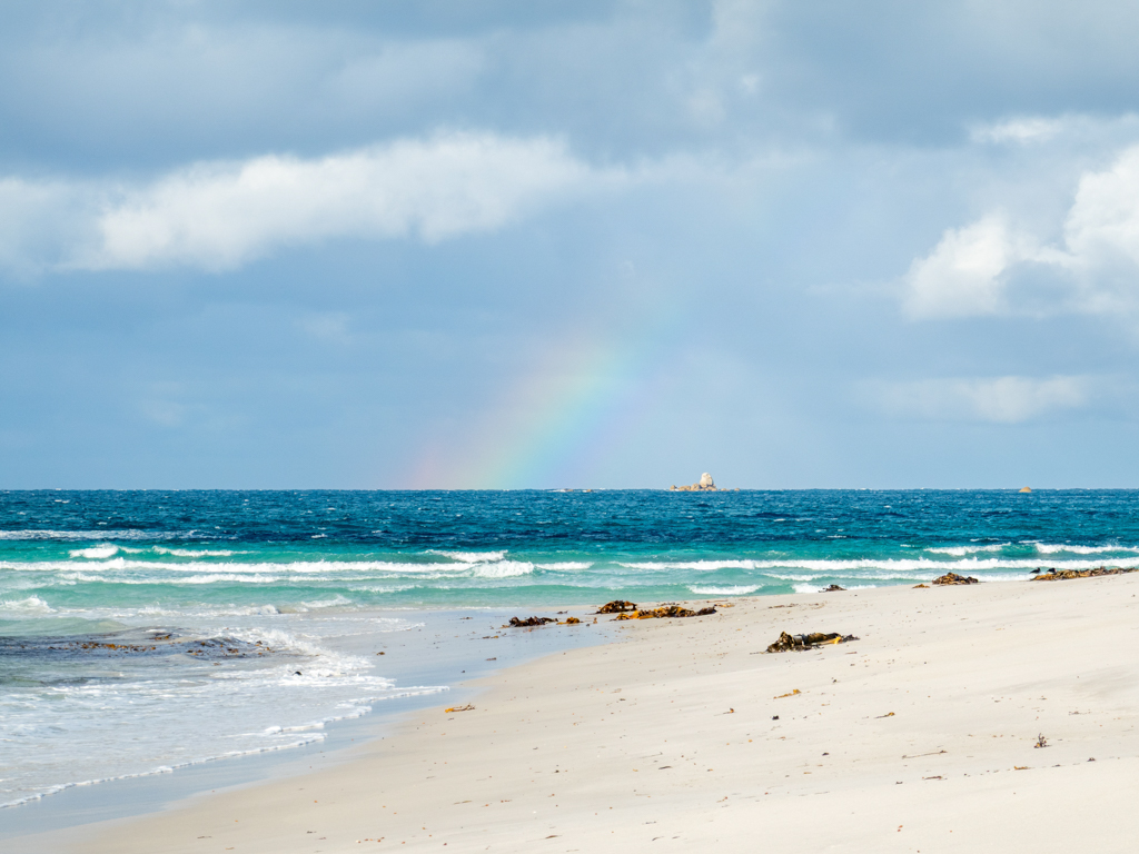 Während der Strandwanderung sehen wir einen Regenbogen am Horizont