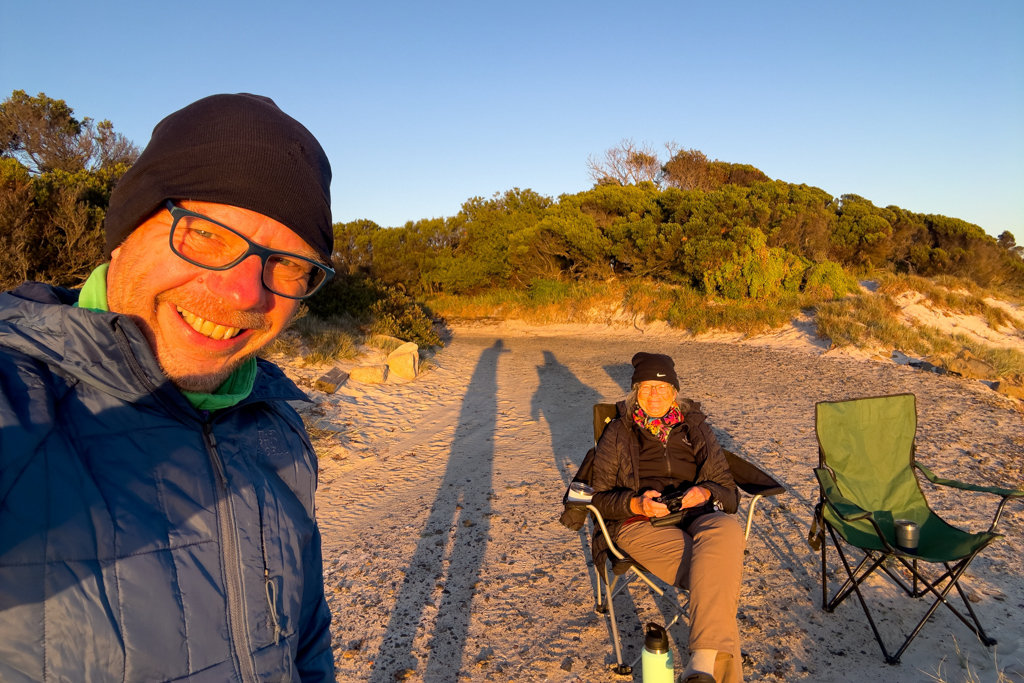 JoMa geniessen nach der kalten Nacht mit einem heissen Kafi den Sonnenaufgang am Strand