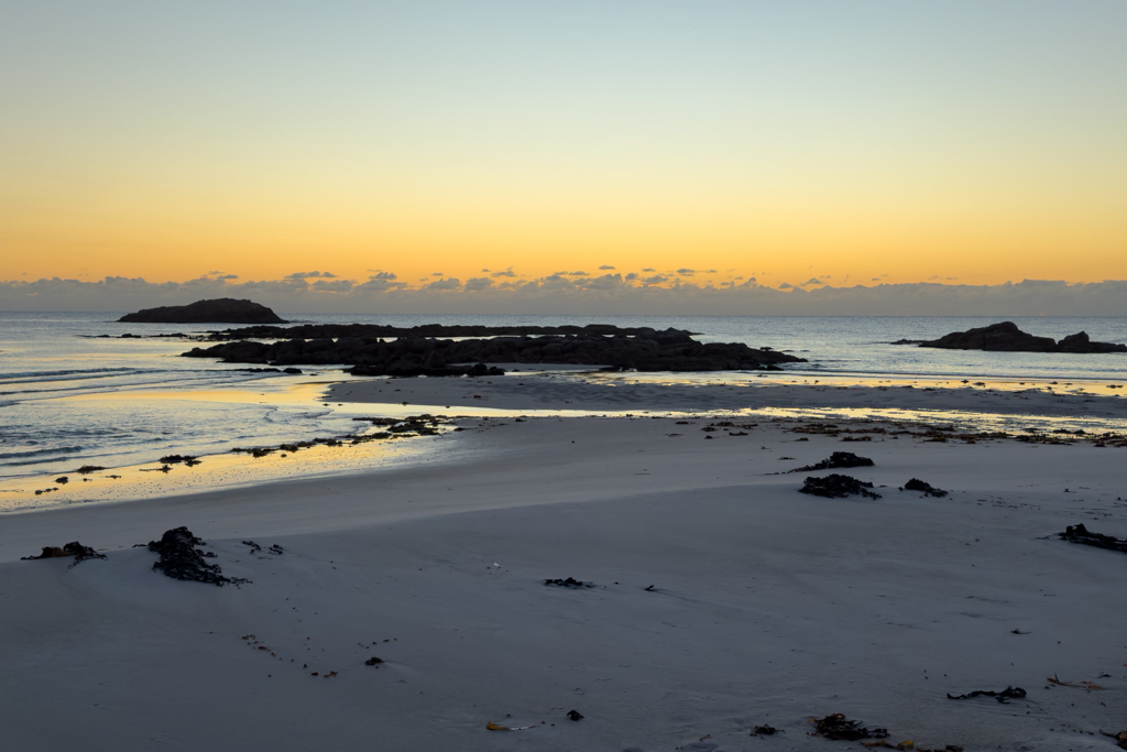 Es ist Ebbe am frühen Morgen - ein Wolkenband verdeckt noch die Sonne am Horizont