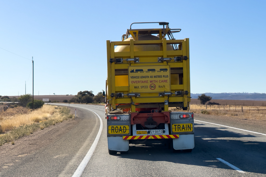 Vor uns ein Road Train mit Hinweistafel, dass er länger als 40 m ist, Überholen mit Vorsicht und dass er max. 90 km/h schnell fährt