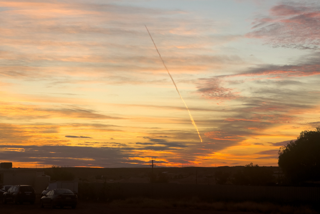 Ein Flugzeug kreuzt quer den Abendhimmel über Coober Pedy