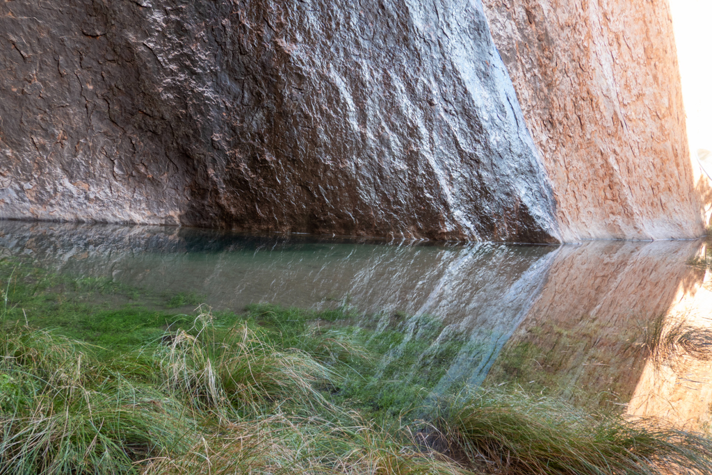 Dort wo das Regenwasser in das Wasserloch herabgelaufen ist färbt sich der sonst rote Sandstein fast schwarz