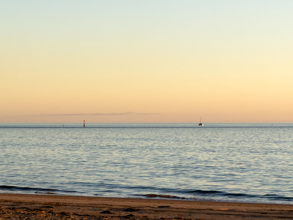 Ein einsames Segelboot liegt vor der Town Beach vor Anker