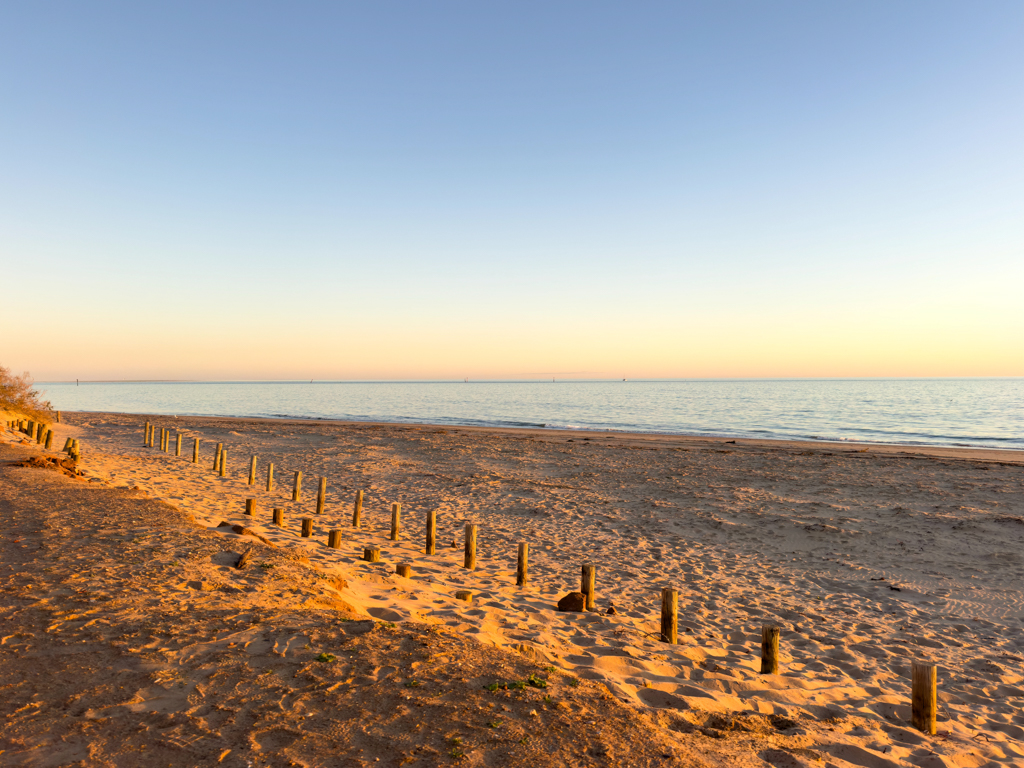 Langsam geht die Sonne an der menschenleeren Town Beach unter.