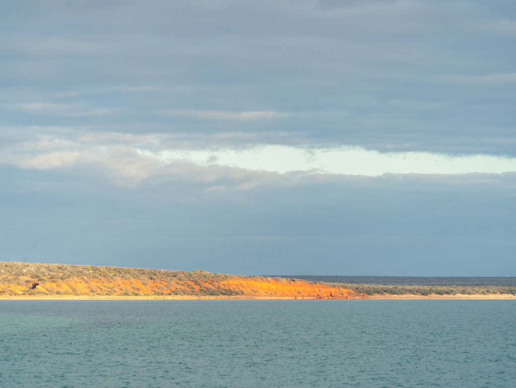 Durch ein Loch in der Wolkendecke bringt die Sonne das Red Cliff zum leuchten
