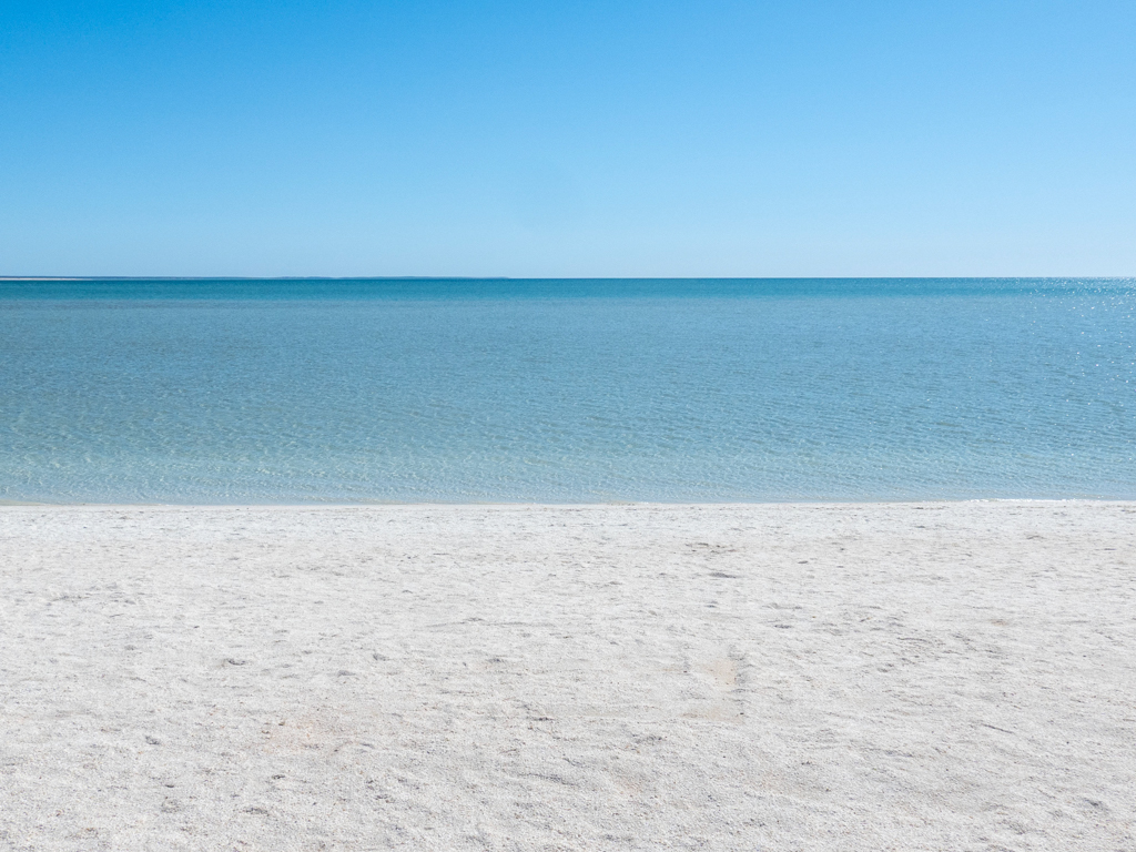 Ein Bild so klar und hell wie von William Turner gemalt. Vorne die weisse Shelly Beach, dann das türkisfarbene flache Wasser mit dem leuchtend blauen Himmel darüber.