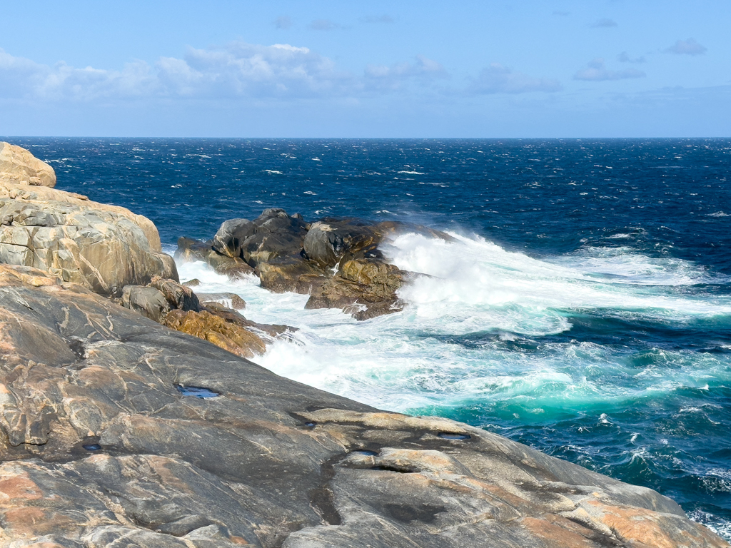 Weisse Gischt schlägt am Felsen hoch - es weht ein steifer Wind
